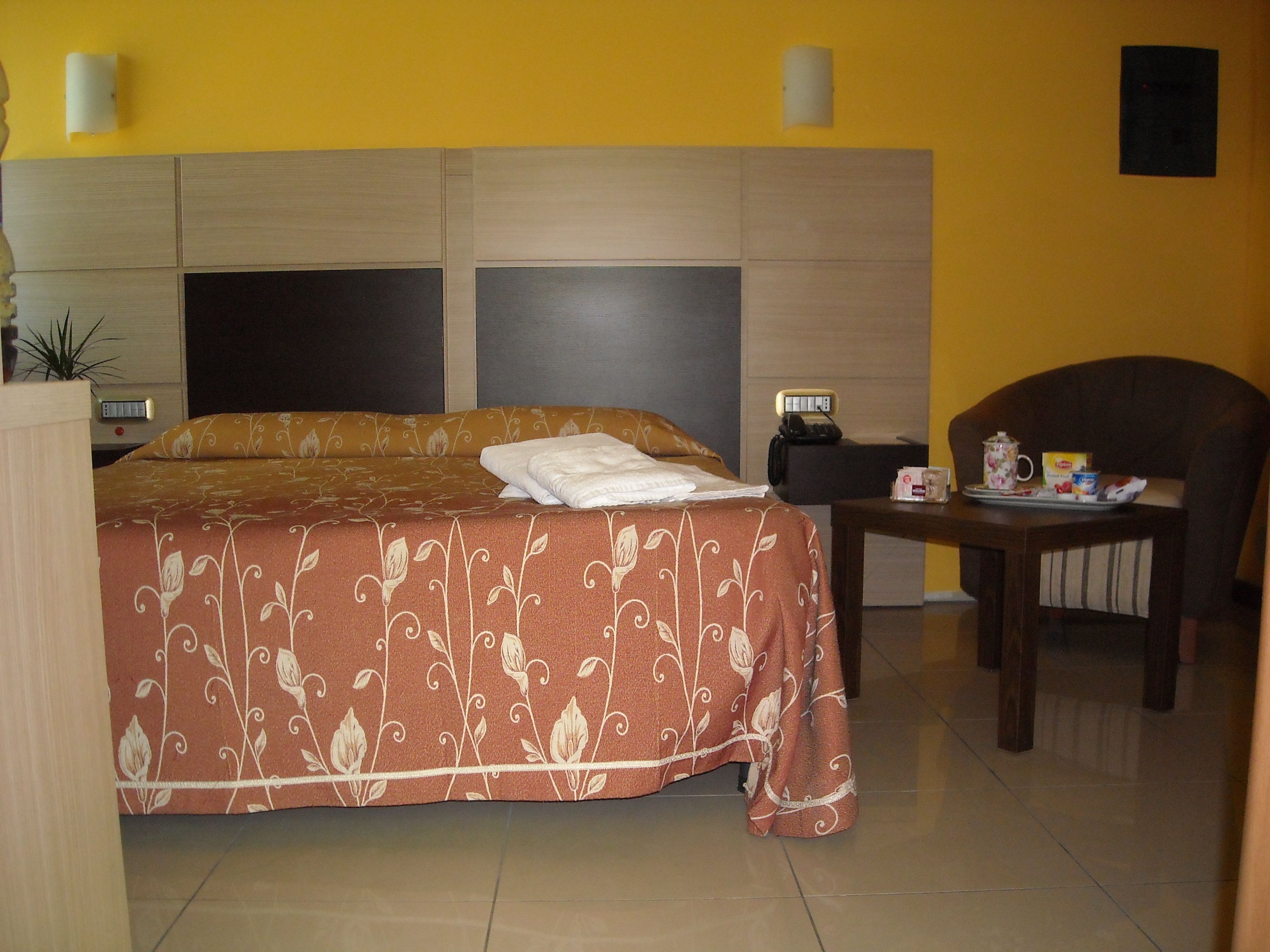 Ein Hotelzimmer mit einem Bett, einem Sessel, einem Tisch und einem Nachttisch.