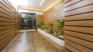 A corridor with wooden panel walls, a tiled floor, and a planter with plants. - Hotel La Piana (Tito)