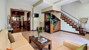 A modern living room with a sofa, coffee table, and a staircase leading to a lower level. - Hotel Vale Verde (Povoacao)
