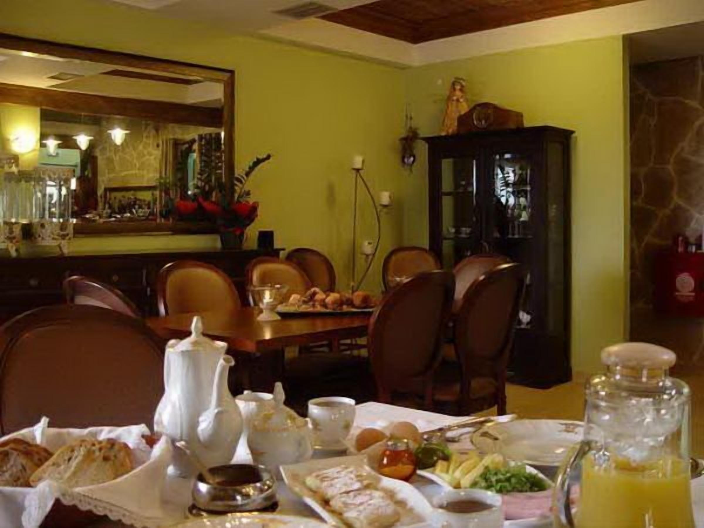 Un comedor con una mesa lista para el desayuno, incluyendo pan, huevos y una jarra de jugo de naranja.