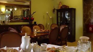 Un comedor con una mesa lista para el desayuno, incluyendo pan, huevos y una jarra de jugo de naranja.