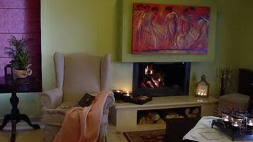 Una sala de estar acogedora con chimenea, un sillón cómodo y un cuadro en la pared.