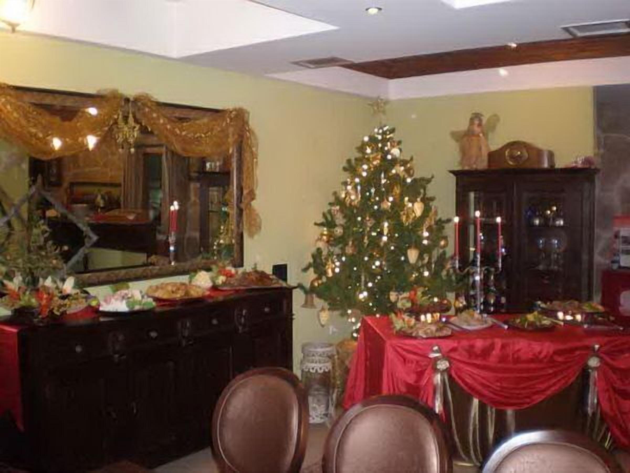 Comedor con un árbol de Navidad, un espejo y mantel rojo.