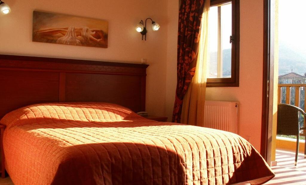 A bedroom with a large bed, a painting on the wall, and a window with curtains.