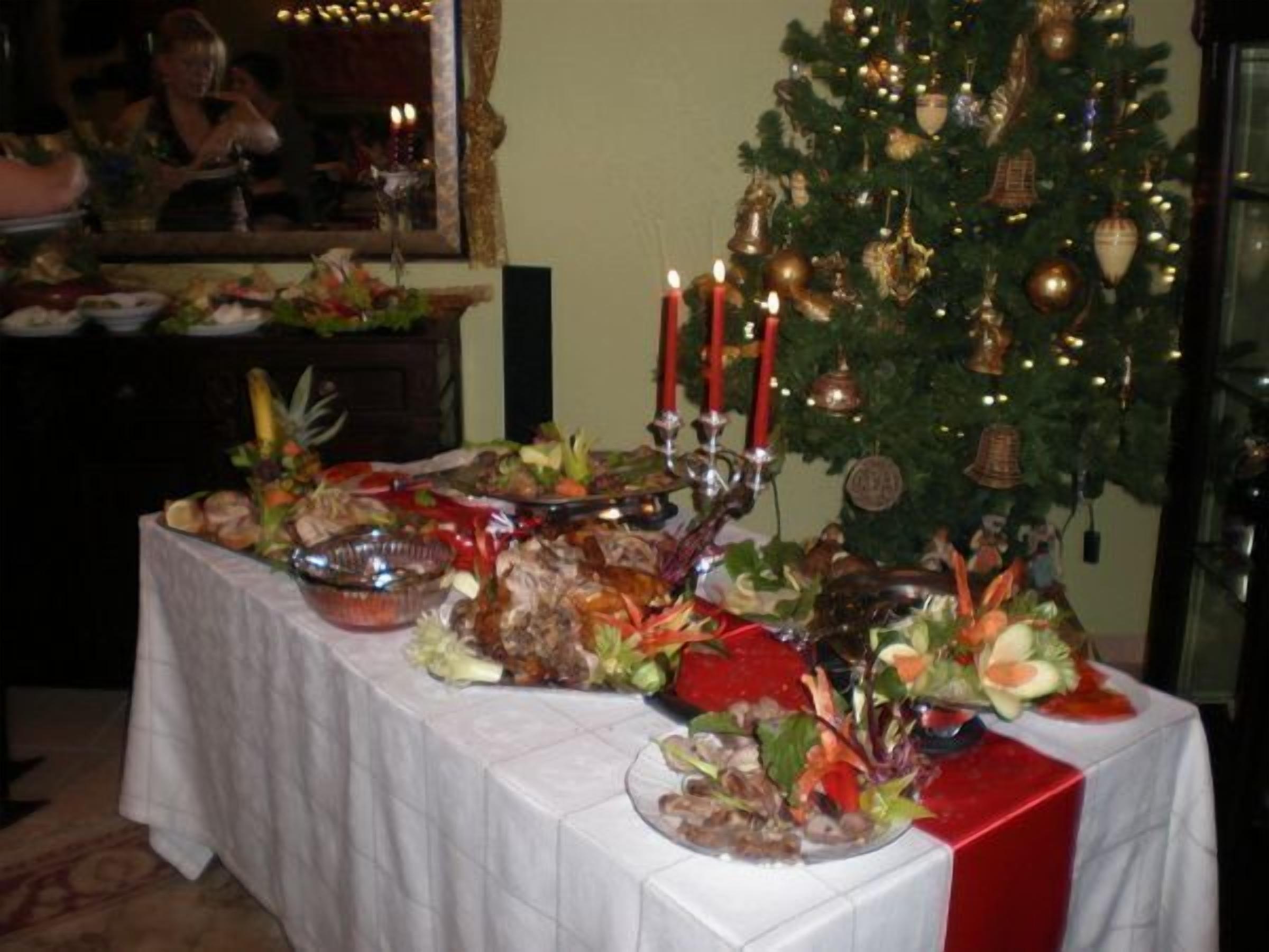 Ein Esstisch mit verschiedenen Speisen und ein Weihnachtsbaum im Hintergrund.