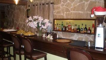 A bar area with a stone wall, multiple hanging light fixtures, a variety of liquor bottles, and a Santa hat on a blender.
