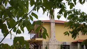 Un edificio amarillo con balcón y un pilar de piedra.