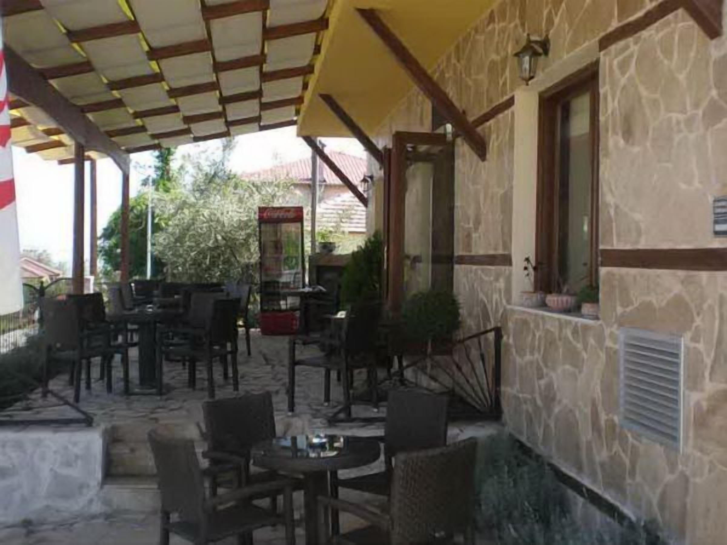 An outdoor patio area with stone walls, wooden furniture, and a yellow awning.