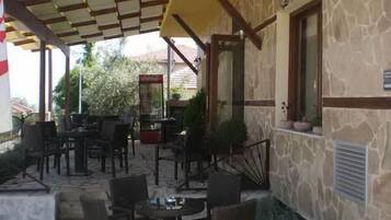 An outdoor patio area with stone walls, wooden furniture, and a yellow awning.