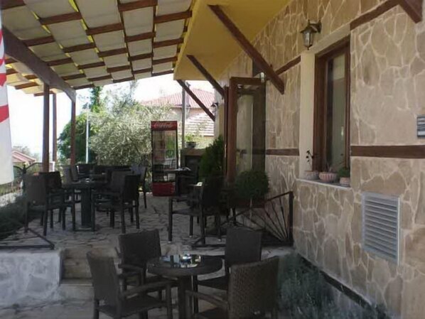 Un patio al aire libre con muros de piedra, mobiliario de madera y un toldo amarillo.