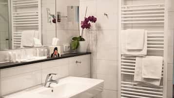 Un baño moderno con un lavabo blanco, espejo y perchero.