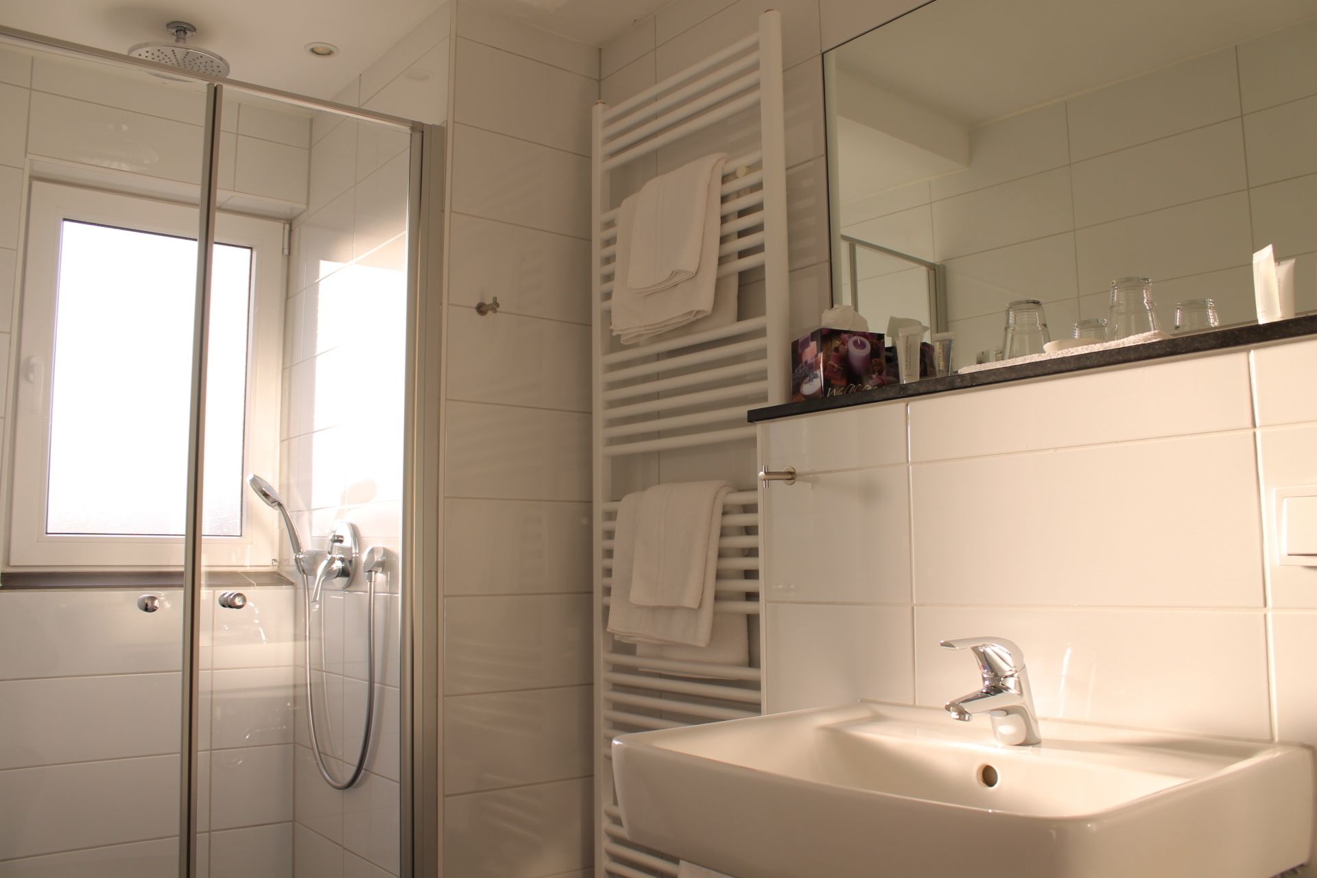 Un baño moderno con cabina de ducha de vidrio, un lavamanos blanco y un espejo sobre él.