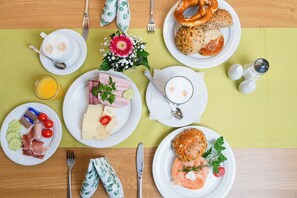A breakfast setting with plates of food, utensils, and a flower centerpiece. - Hotel Gasthof Zum Rössle (Altenstadt)
