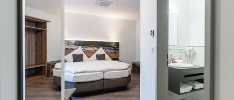 A modern bedroom with a large bed, a headboard with a cityscape view, a bedside table, and a built-in wardrobe.