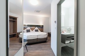 Quarto moderno com uma cama grande, cabeceira com vista para a cidade, mesa de cabeceira e roupeiro embutido.