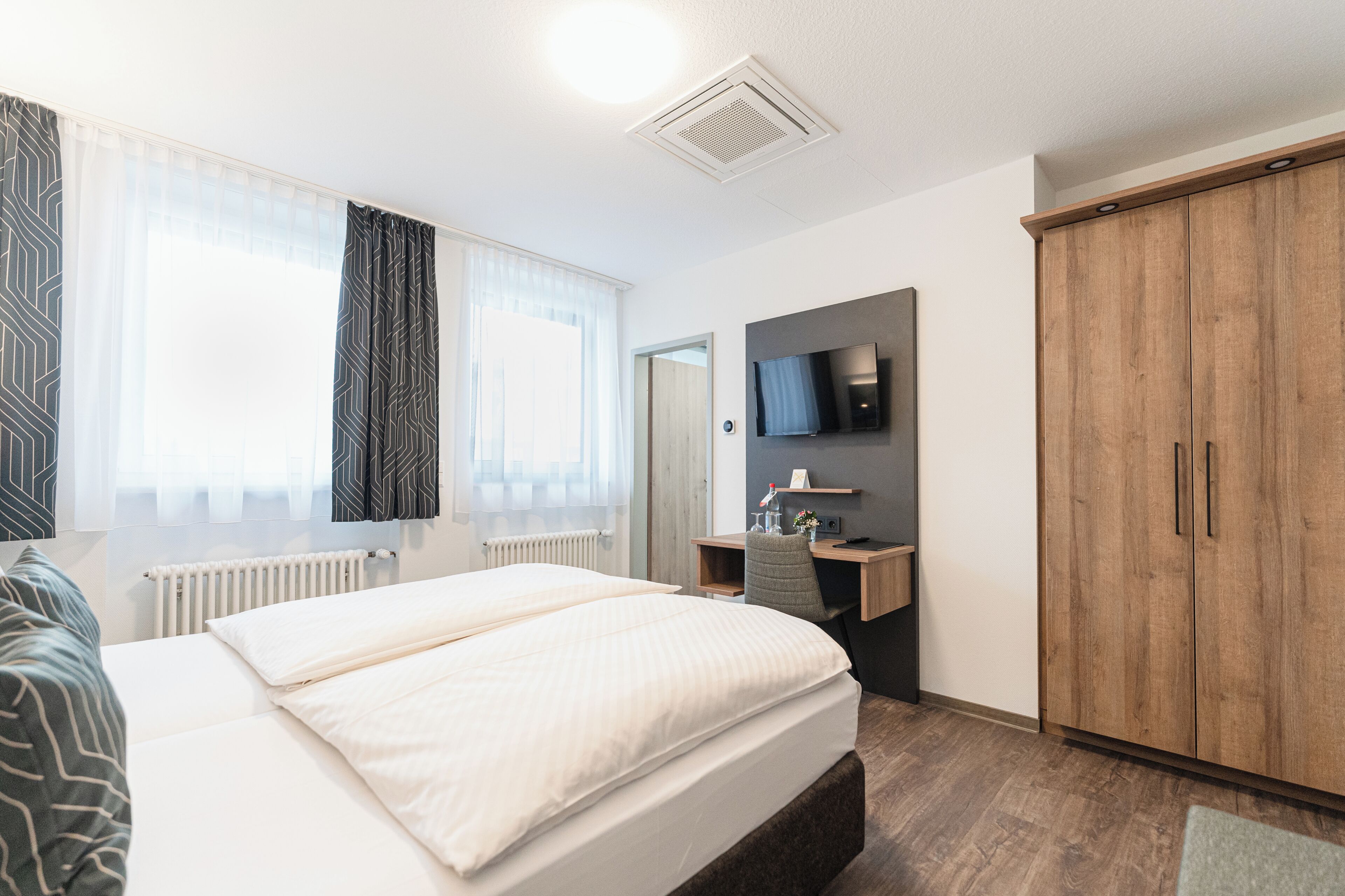 Una habitación de hotel con cama, escritorio, televisión y armario.