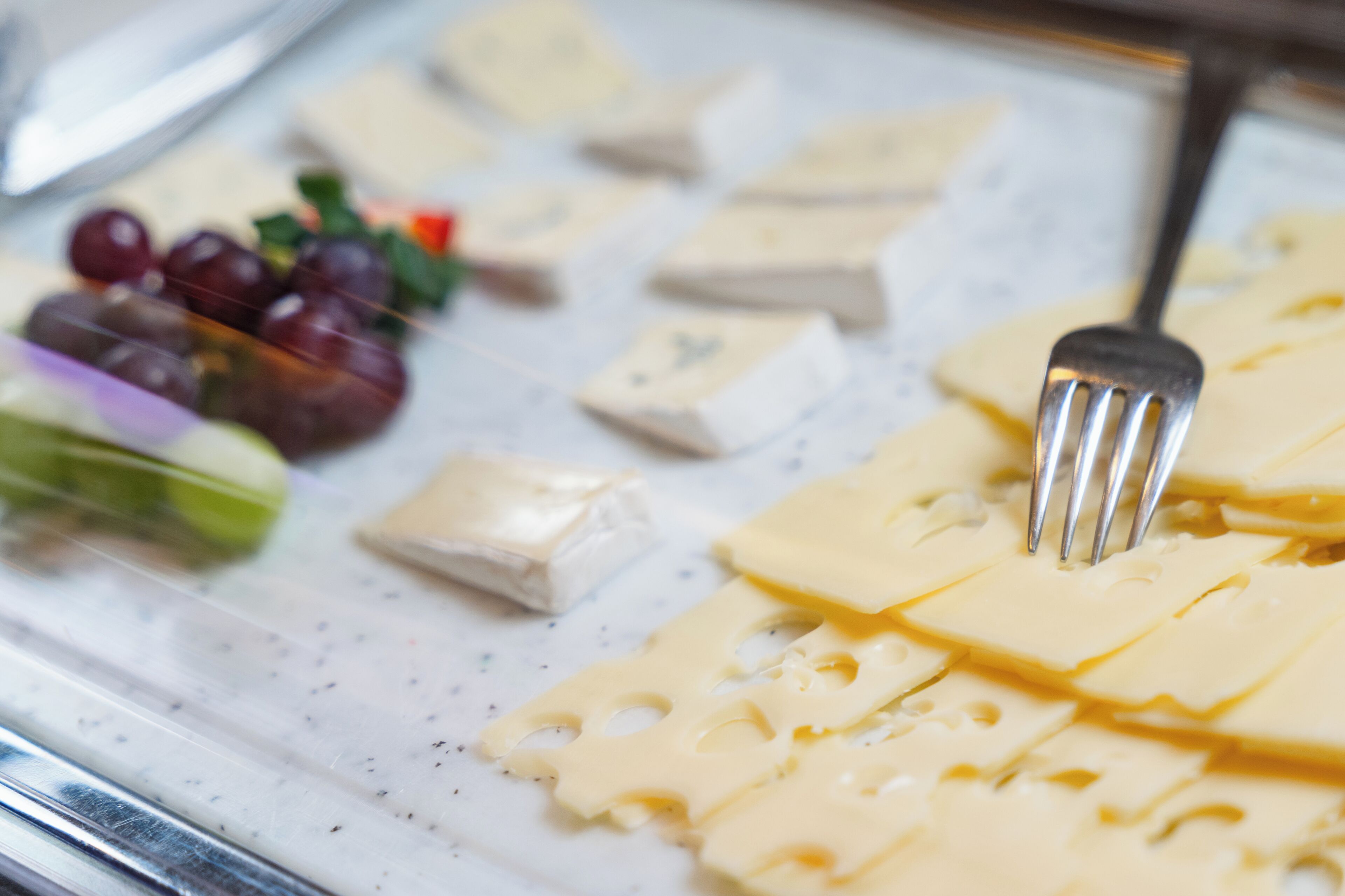 A cheese board with various cheeses and grapes.