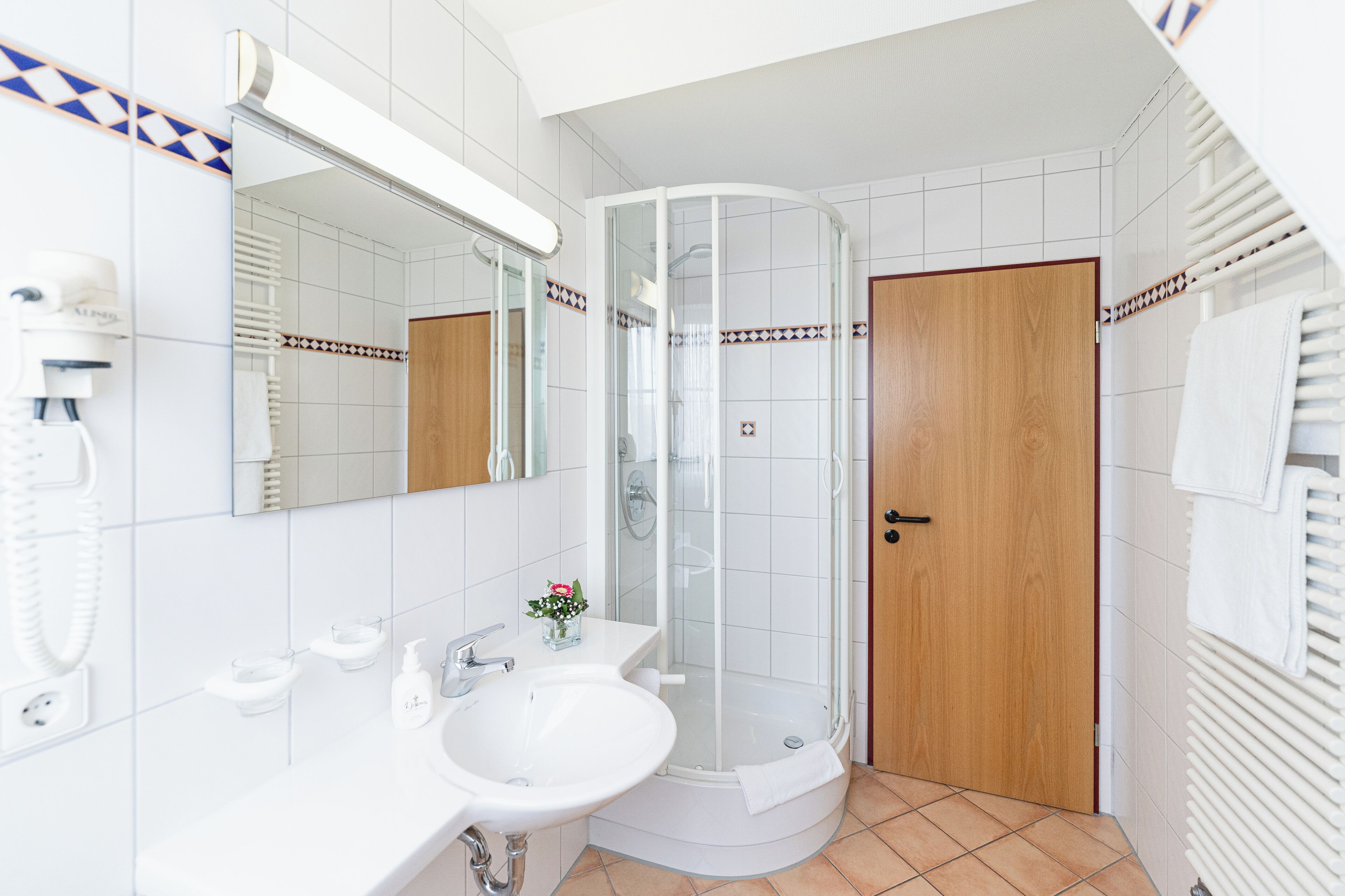 Un baño moderno con ducha de vidrio, un lavamanos y un espejo.