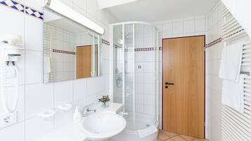 Un baño moderno con ducha de vidrio, un lavamanos y un espejo.