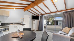 A modern kitchen with a dining area, a sofa, and a large sliding glass door to the outside. - Tasman Holiday Parks - Te Anau (Te Anau)
