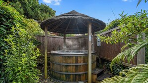 A wooden hot tub with a thatched roof, surrounded by a wooden fence and lush greenery. - Tasman Holiday Parks - Te Anau (Te Anau)