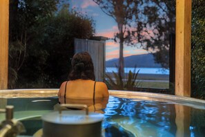 A person in a hot tub with a view of a sunset and mountains. - Tasman Holiday Parks - Te Anau (Te Anau)