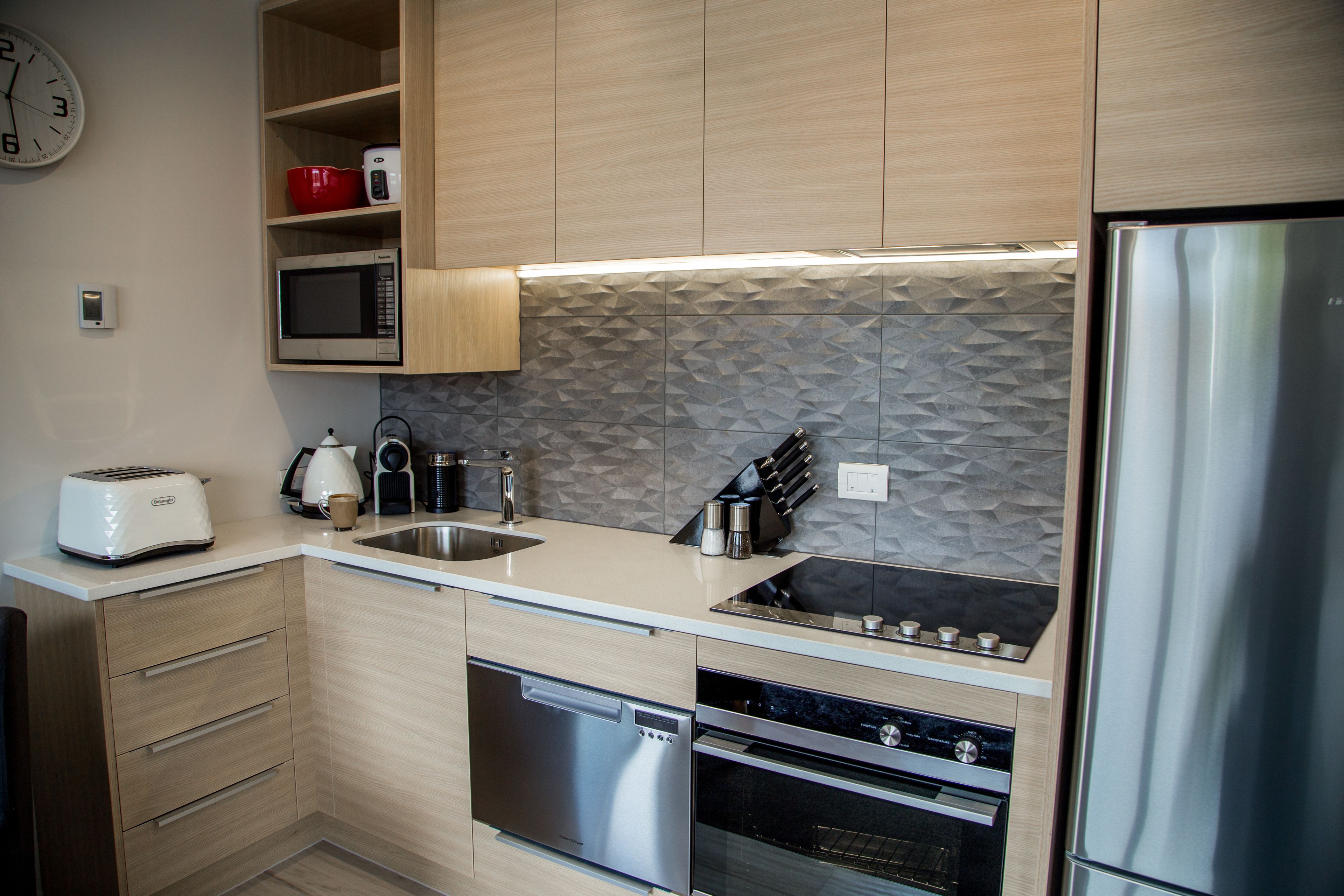 A modern kitchen with wooden cabinets, a microwave, a toaster, a sink, and a dishwasher.