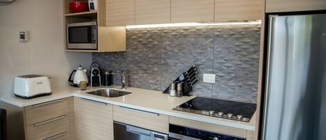 A modern kitchen with wooden cabinets, a microwave, a toaster, a sink, and a dishwasher.