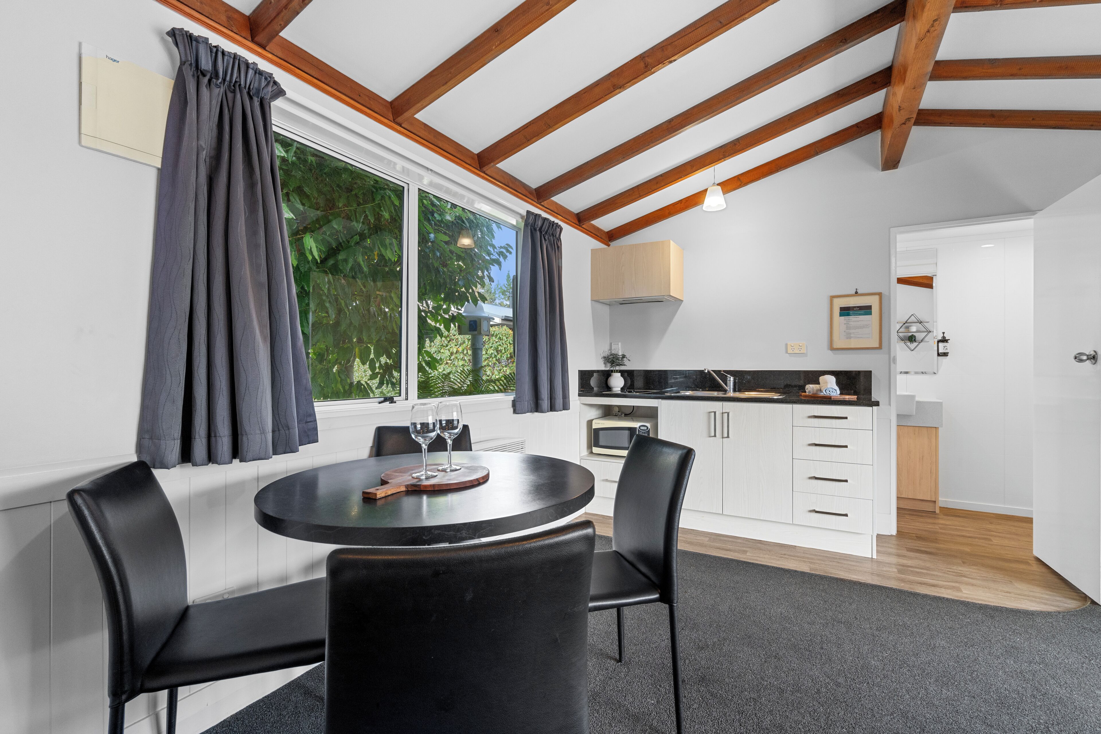 A modern kitchen with white cabinets, a black countertop, and a window with curtains.