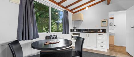 A modern kitchen with white cabinets, a black countertop, and a window with curtains.