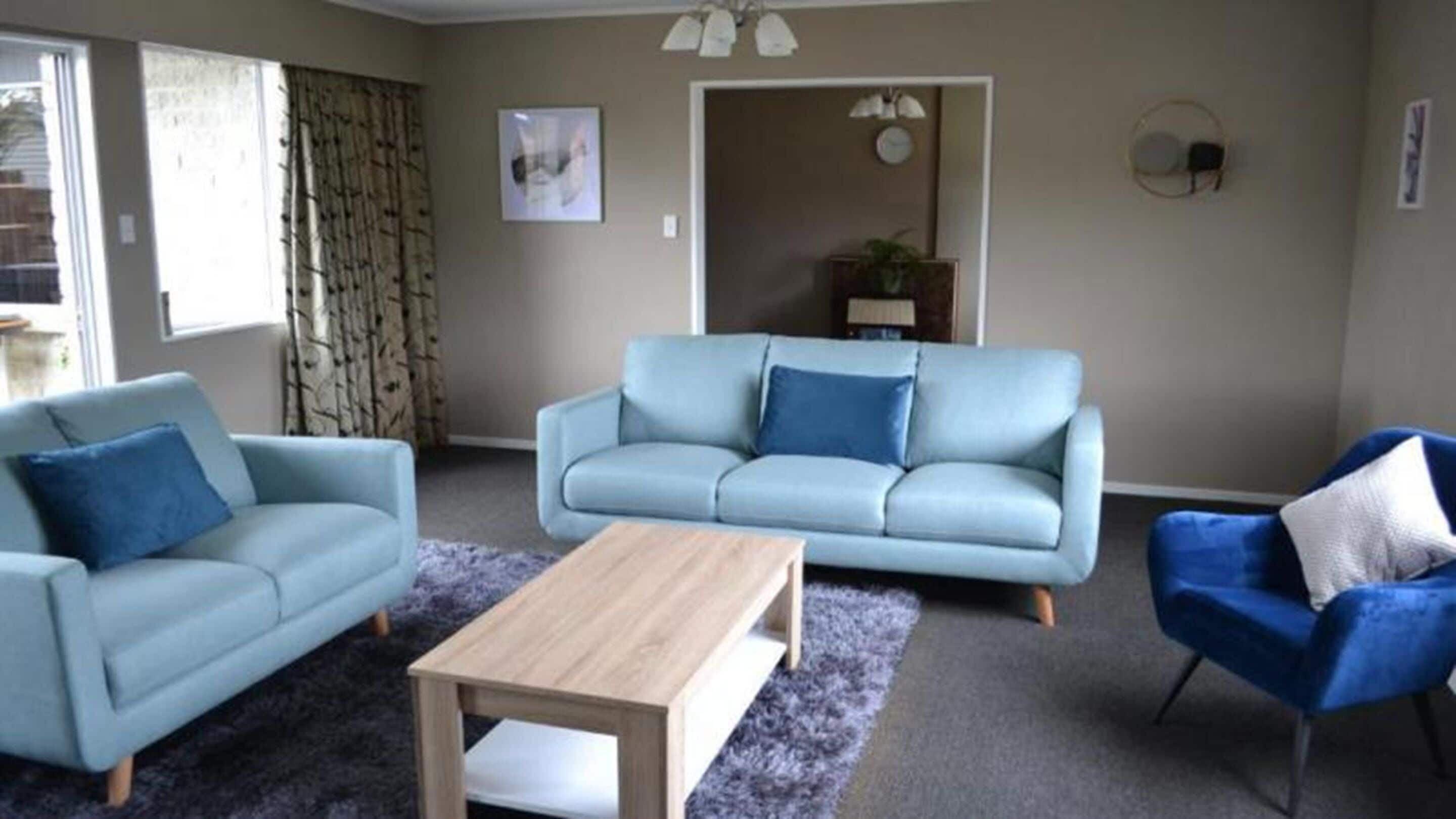 A living room with a light blue sofa, a matching armchair, and a wooden coffee table.