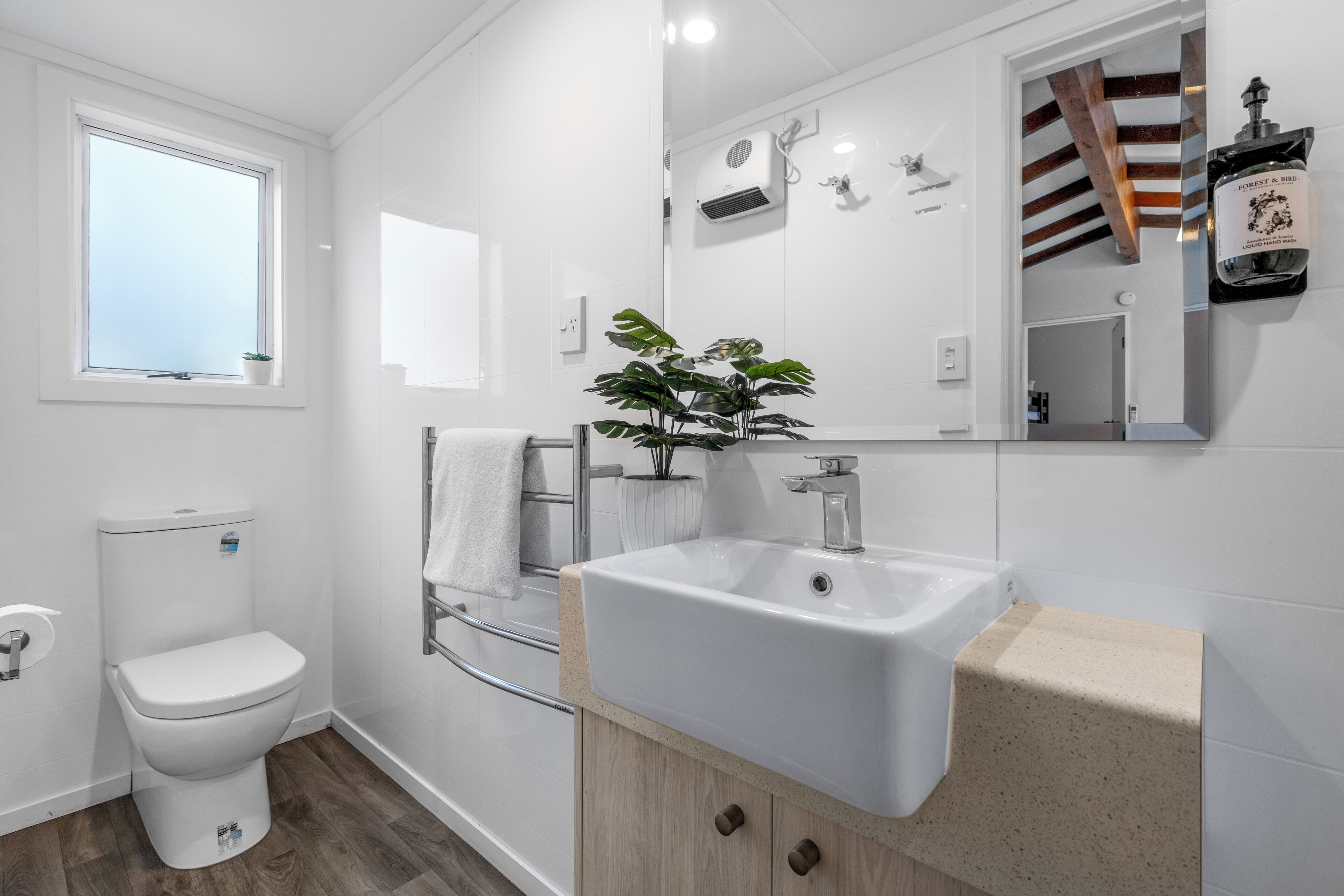 A modern bathroom with a toilet, sink, and mirror.