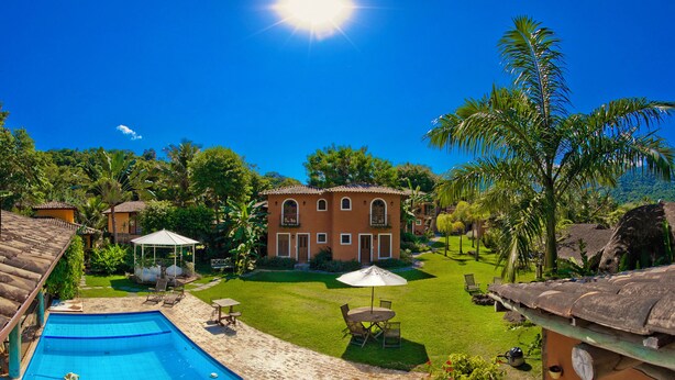 Un área de piscina con una piscina azul cristalina, un patio amueblado al aire libre y un césped bien cuidado.