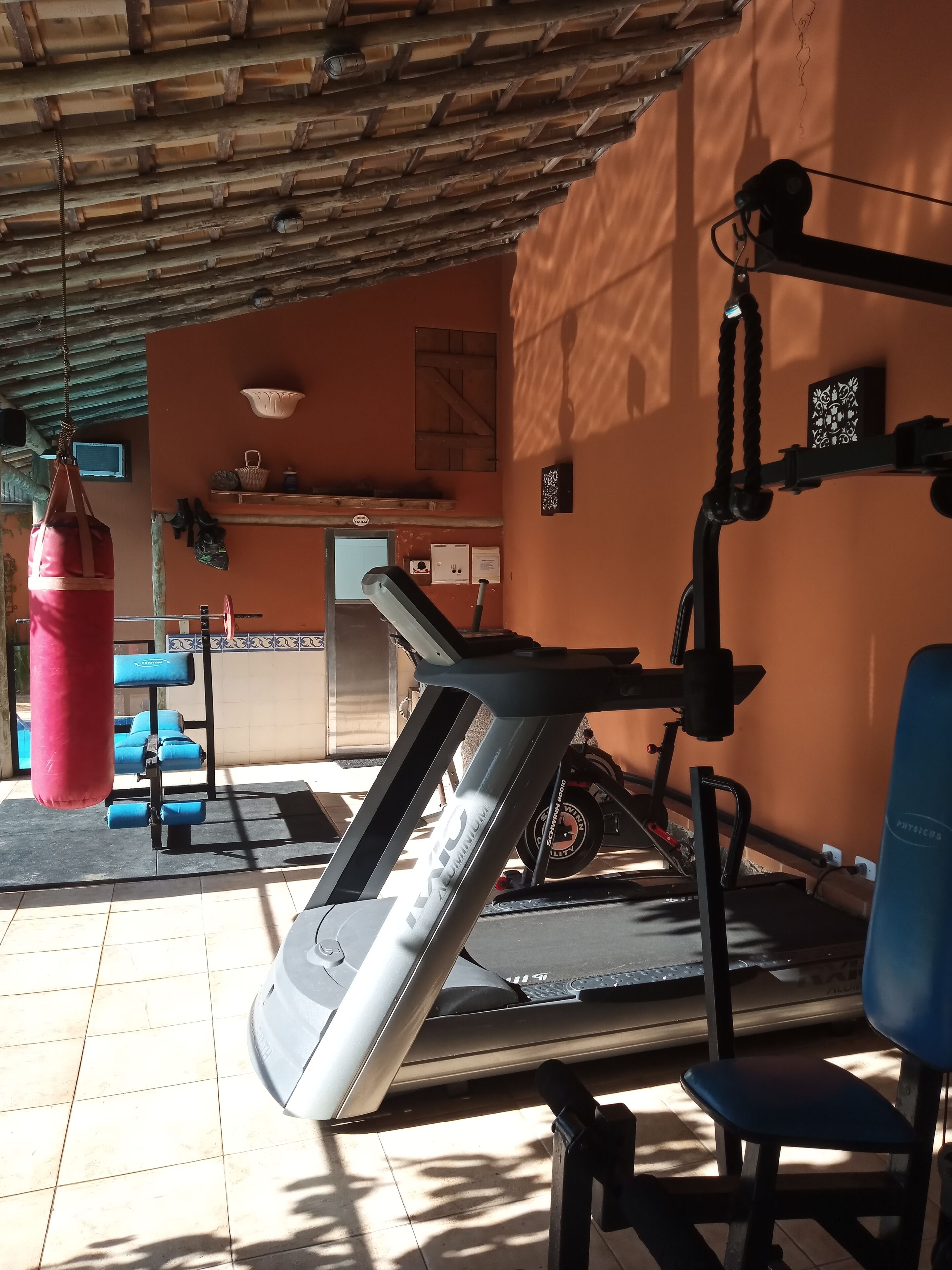 Un gimnasio con equipo de ejercicio, un saco de boxeo y una silla azul.
