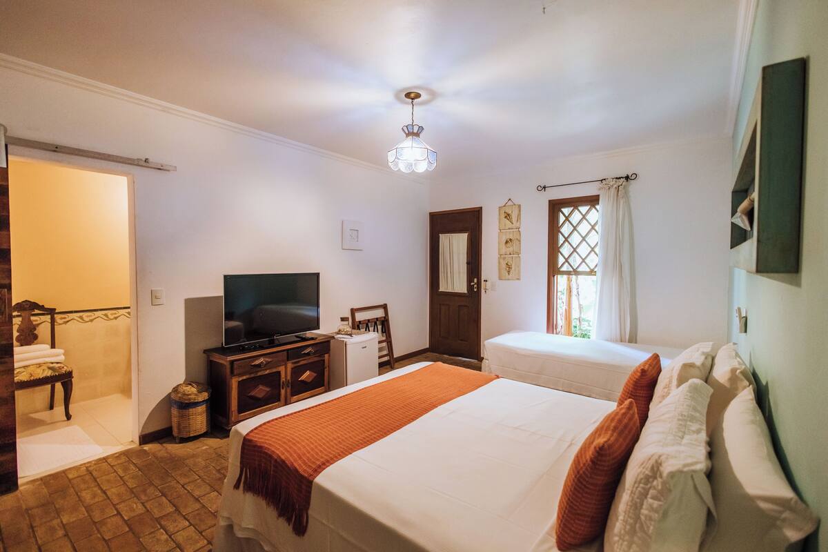 A hotel room with a bed, a television, a desk, and a window with curtains.