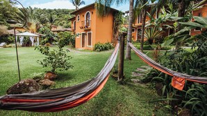 Una hamaca en un jardín exuberante, con una casa al fondo.
