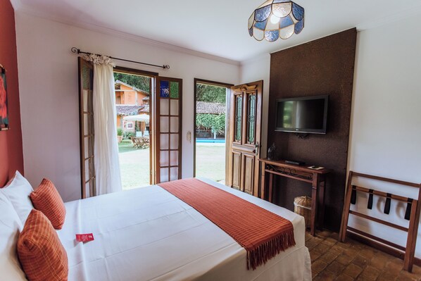 A hotel room with a bed, a TV, a desk, and a view of the outside.