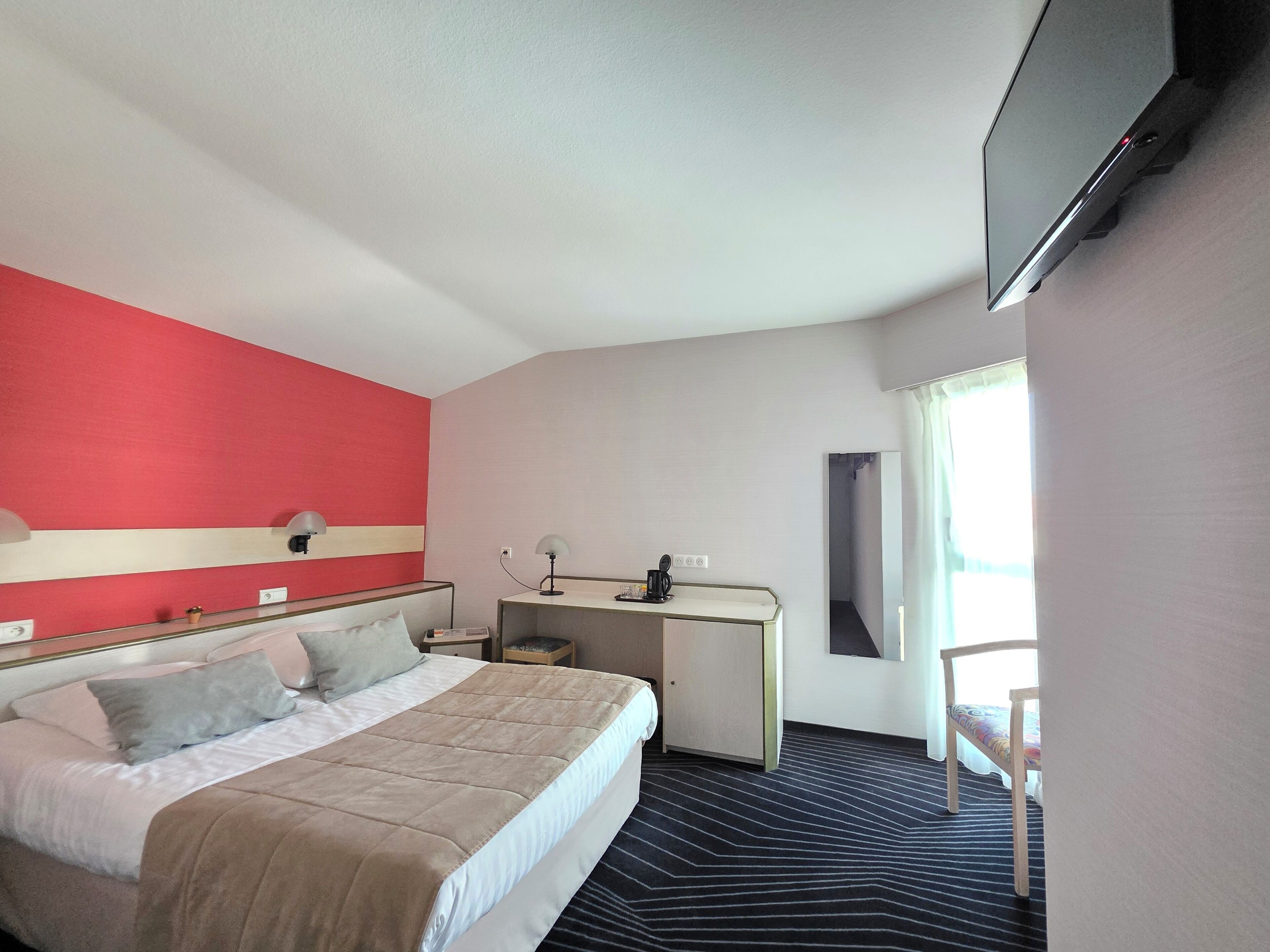Una habitación de hotel con cama, escritorio y televisión.