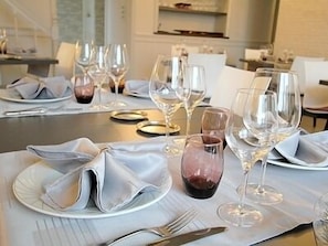 A dining table set with plates, cutlery, and wine glasses, indicating a formal dining arrangement.