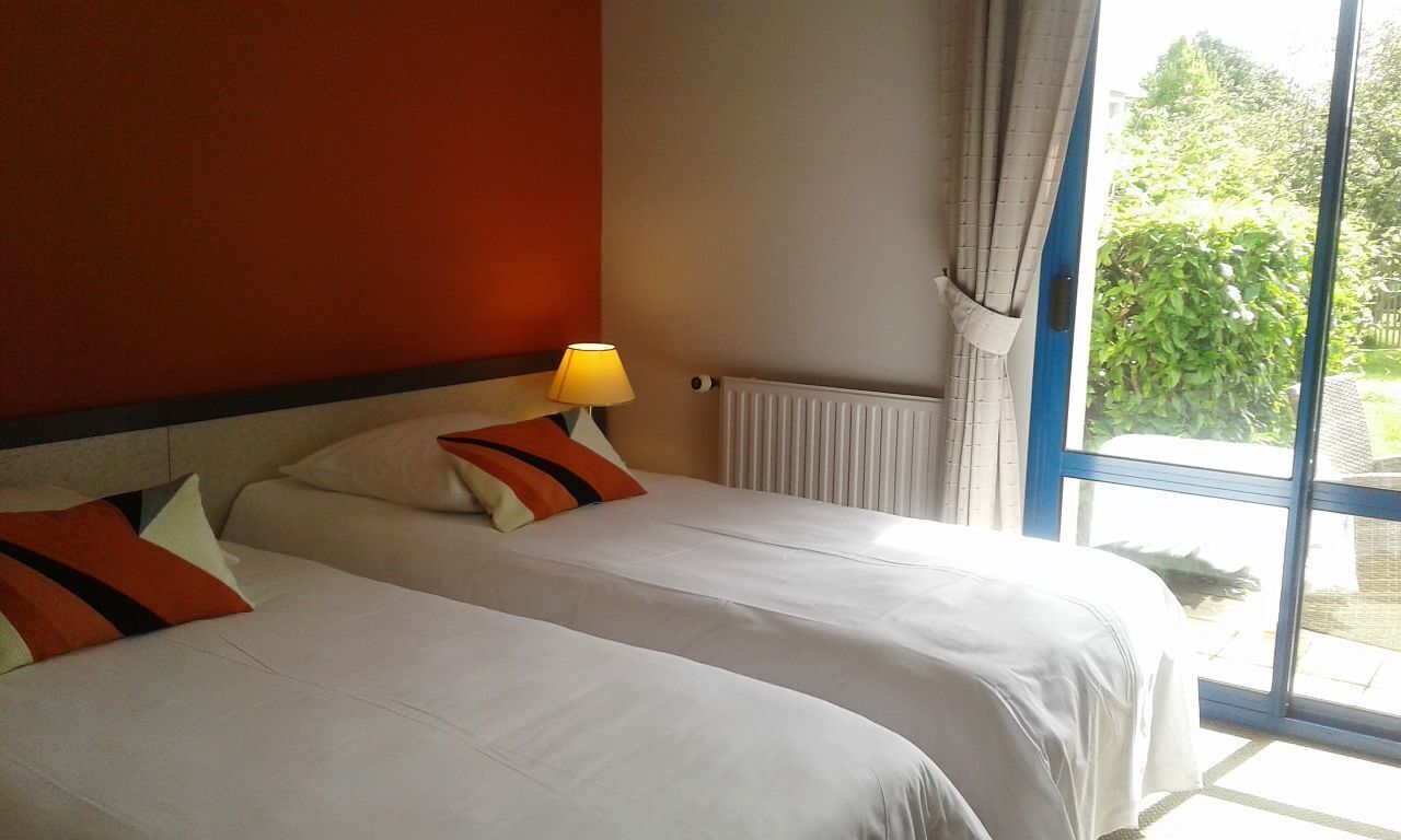 Una habitación de hotel con dos camas, una ventana con cortinas y una lámpara en la mesita de noche.