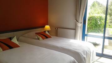 Una habitación de hotel con dos camas, una ventana con cortinas y una lámpara en la mesita de noche.