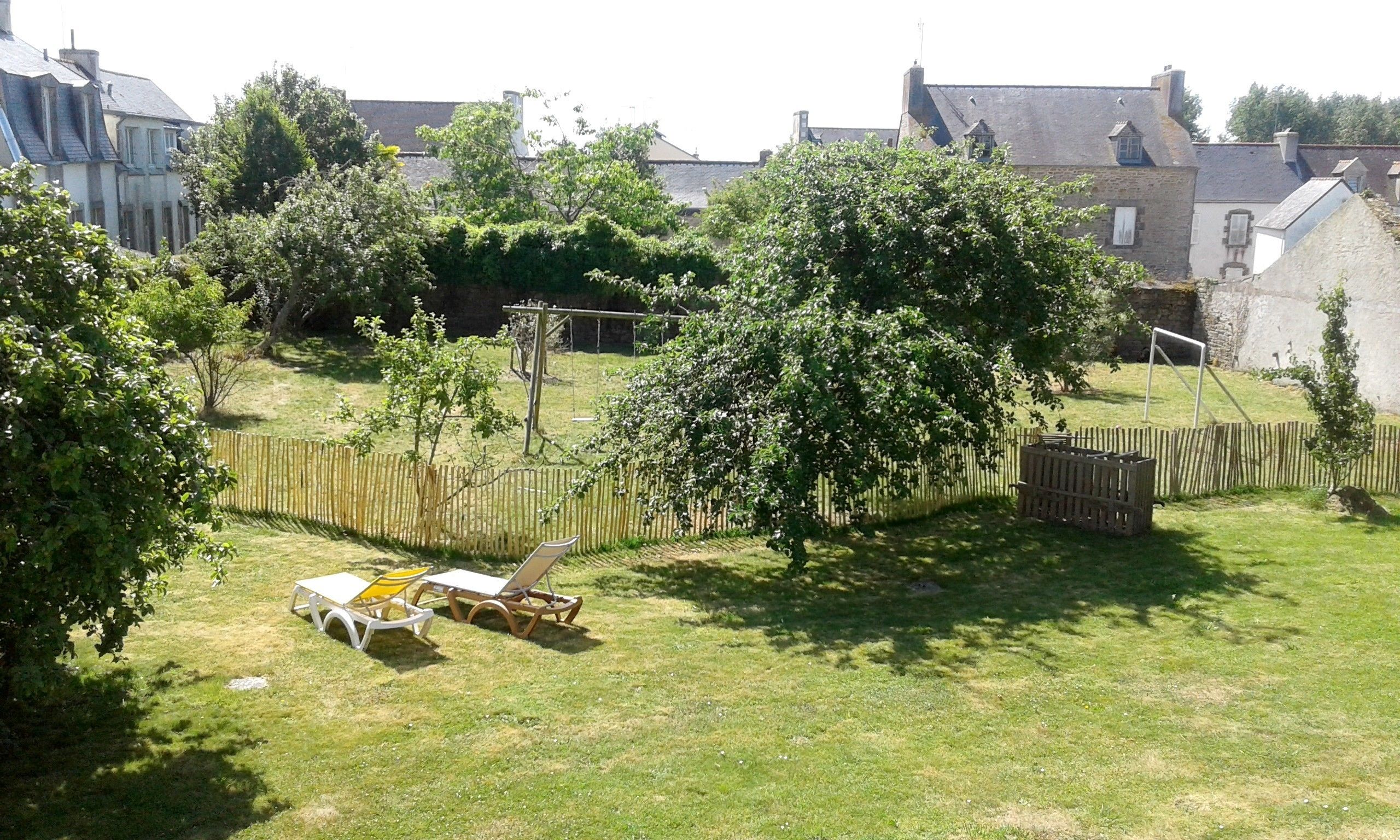 A backyard with a swing set, a wooden fence, and a lawn.