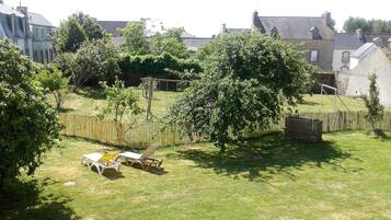 A backyard with a swing set, a wooden fence, and a lawn.