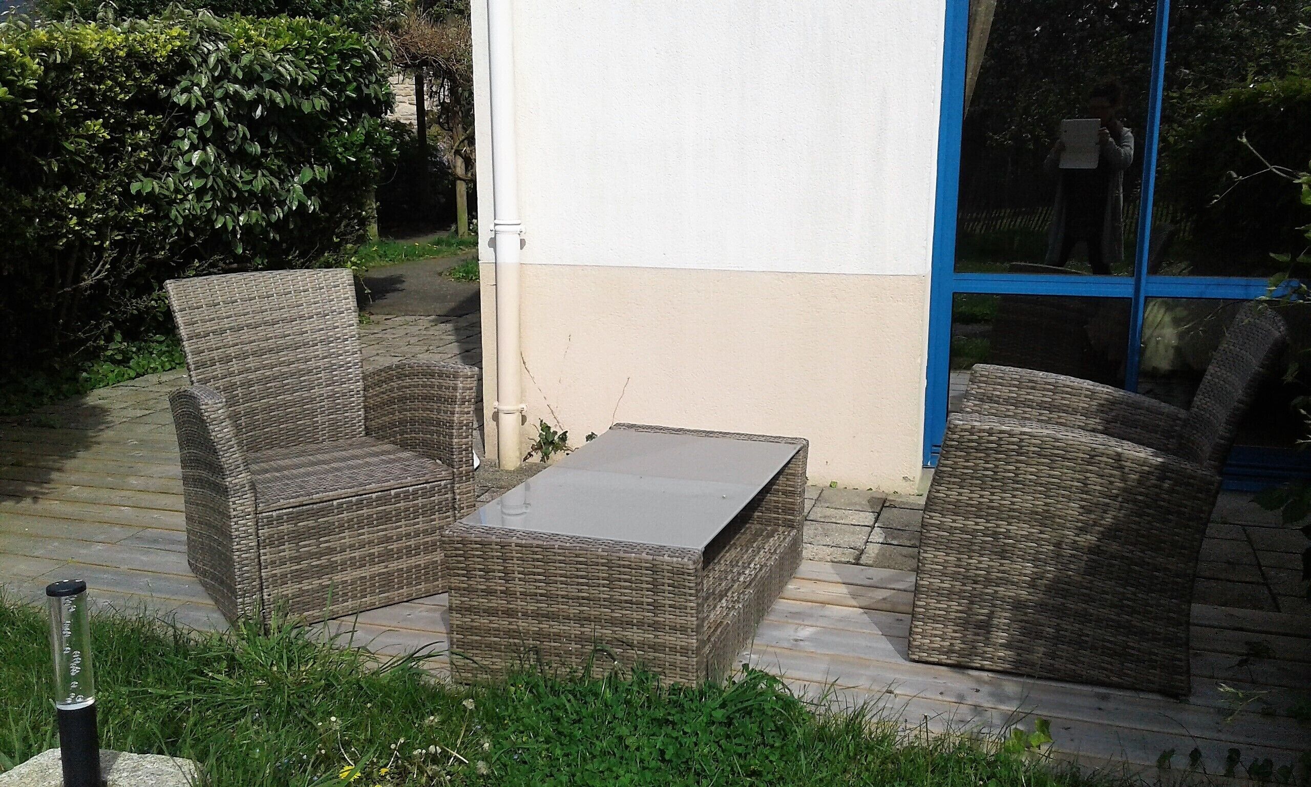 A patio with wicker furniture, a table, and a blue-framed window.