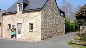 Un edificio de piedra con techo inclinado, una zona de recepción y un letrero que indica que es un hotel, bar y restaurante.