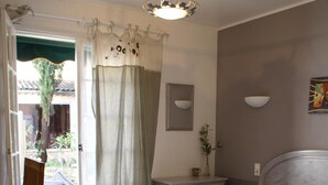 A bedroom with a bed, a nightstand, a chair, and a view of the outside. - Hôtel Le Petit Manoir Provence (Les Angles)