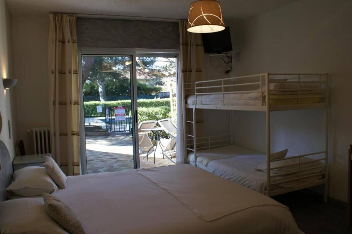 Une chambre avec un lit superposé, un bureau et une chaise, située près d’une porte-fenêtre coulissante donnant sur un espace extérieur.