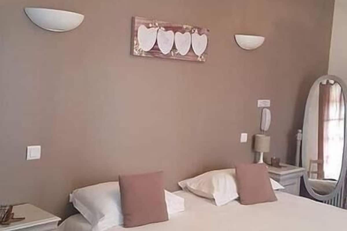 Une chambre d’hôtel avec un grand lit, deux tables de chevet, une commode, un miroir et une œuvre d’art accrochée au mur.