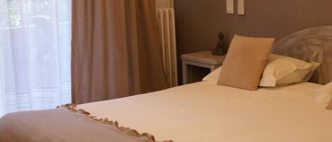 A hotel room with a bed, a bedside table with a lamp, and a wall-mounted light.