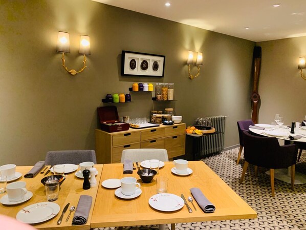 A dining area with a wooden table set for four, equipped with plates, cutlery, and glasses. - Le Cobh (Ploërmel)